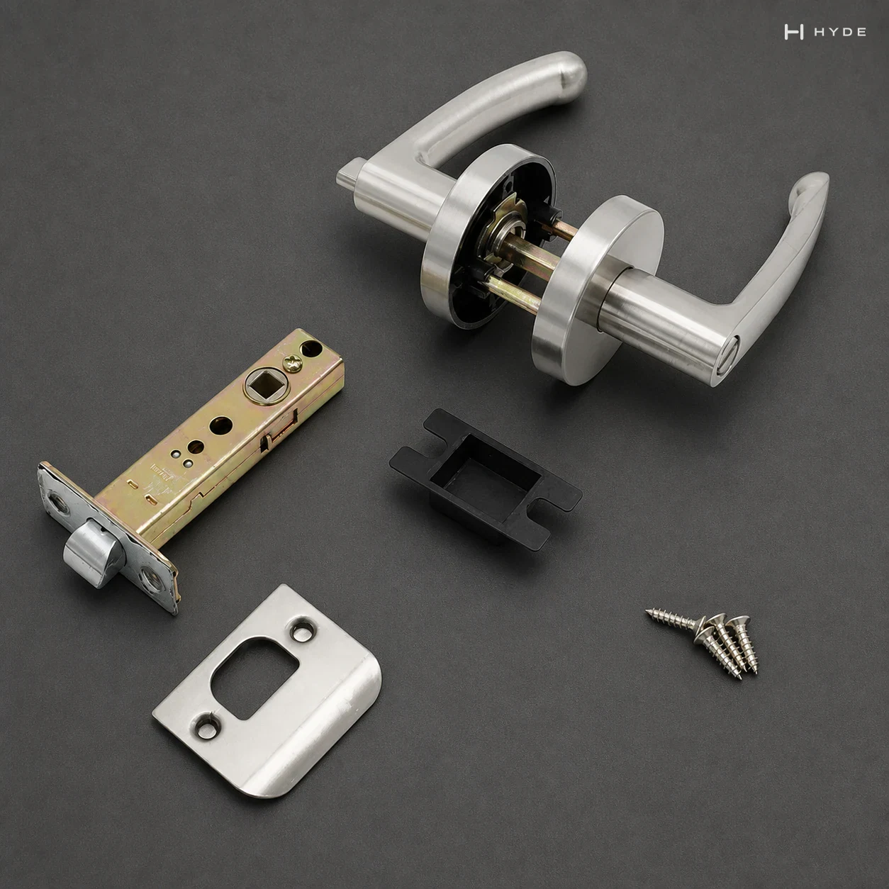 Conjunto completo de fechadura tubular com maçaneta sobre fundo escuro: duas maçanetas em roseta com o quadrado e o mecanismo à vista, a lingueta tubular, a contra-testa, a placa e três parafusos de fixação — todas as peças no mesmo acabamento