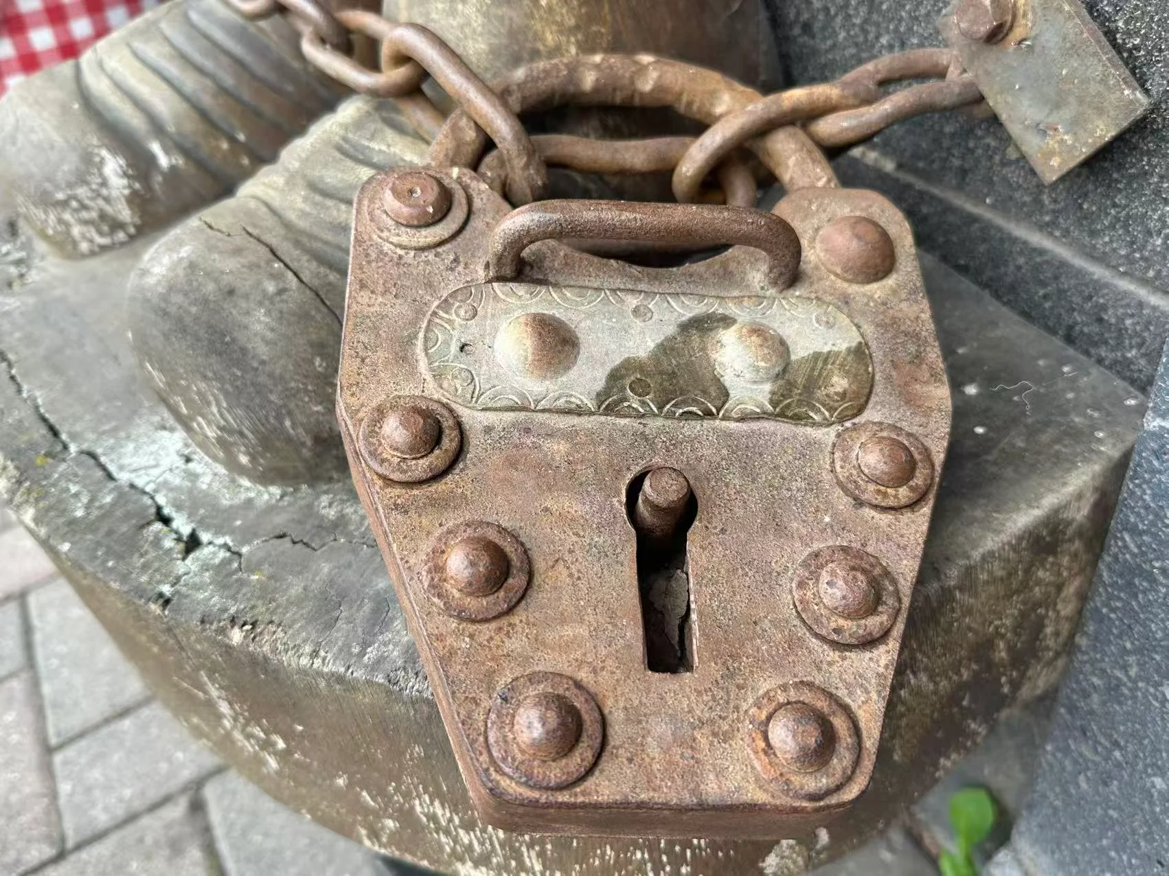 As found, on the stone plinth — the chain is slack and the lock secures nothing