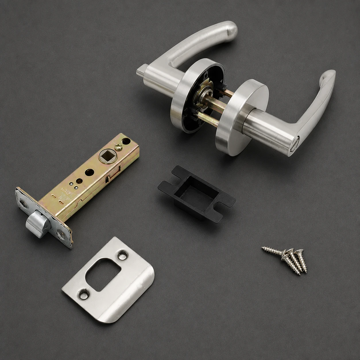 Juego completo de cerradura tubular de manilla sobre fondo oscuro: dos manillas sobre roseta con el cuadradillo y el mecanismo a la vista, el picaporte tubular, el cerradero, la placa y tres tornillos de fijación —todas las piezas en un mismo acabado